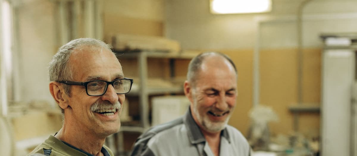 Two experienced craftsmen sharing a laugh in their workshop