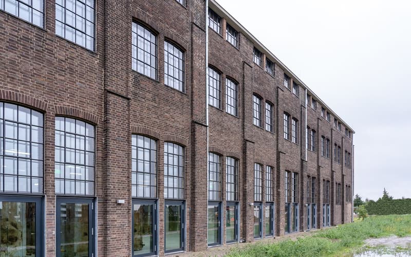 A converted brick mill building with tall arched windows in commercial use