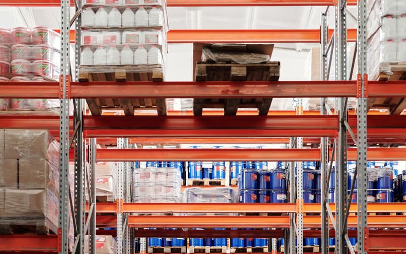 Pallets of stock on orange racking in a bright, orderly warehouse