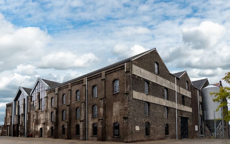 A complex of old brick warehouse buildings under a bright cloudy sky