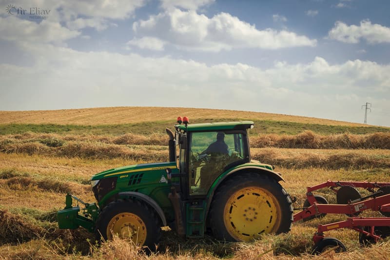Tractor pulling a plough across a golden field under a big sky