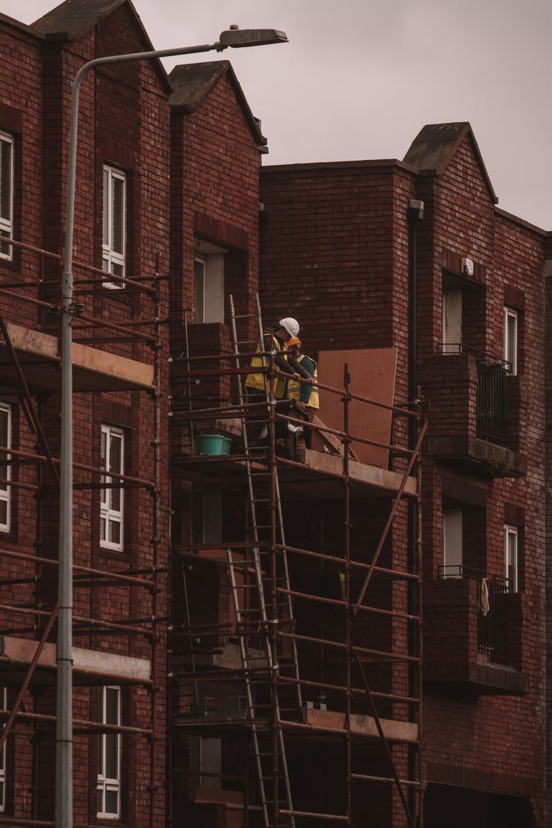 Builders on scaffolding renovating a red-brick building