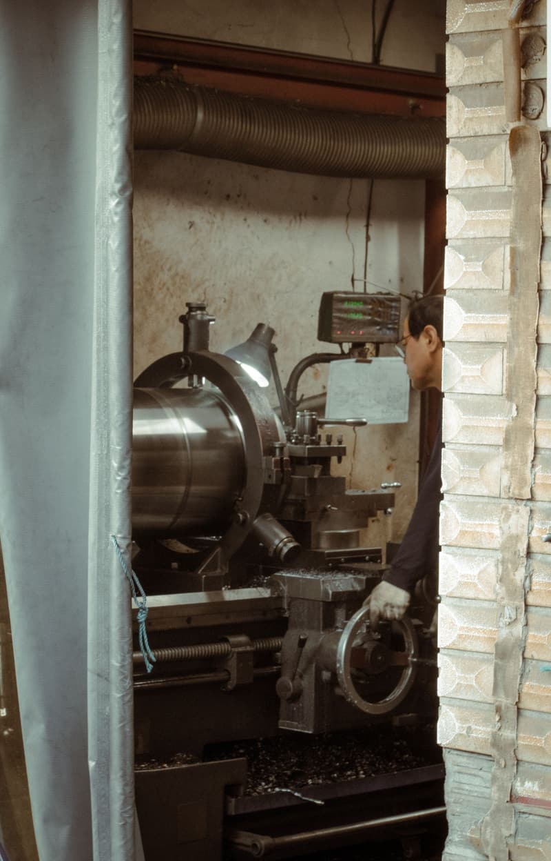 Machinist operating a lathe by the light of a workshop window