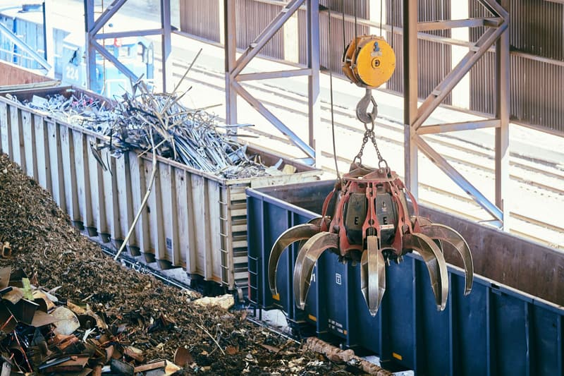 Overhead claw crane sorting scrap metal inside a recycling facility